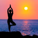 girl doing yoga asanam in beach in sunset